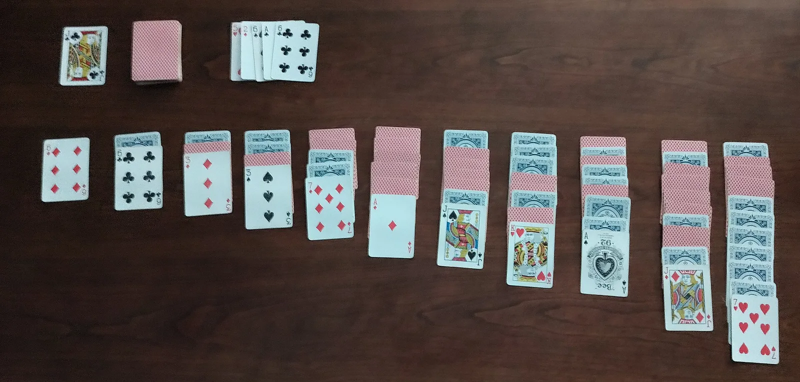 Cartes de deux jeux disposées en longues colonnes sur une table en bois